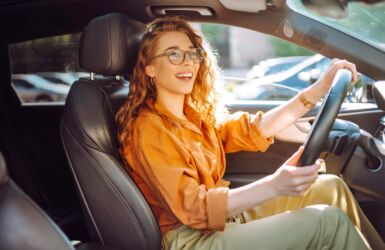 Glimlachende autobestuurder kijkt lachend uit het raam tijdens het autorijden